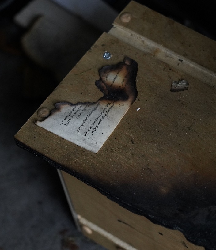 En bränd pappersbit på en sotad trälåda.