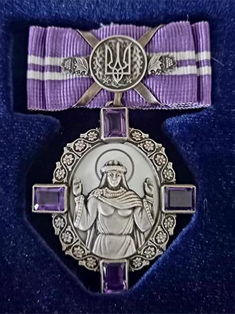 Utm&auml;rkelsen Prinsessan Olgas orden, en silvermedalj med motiv av helgon, utsmyckad med lila band och lila stenar. Ligger mot bl&aring; sammet.